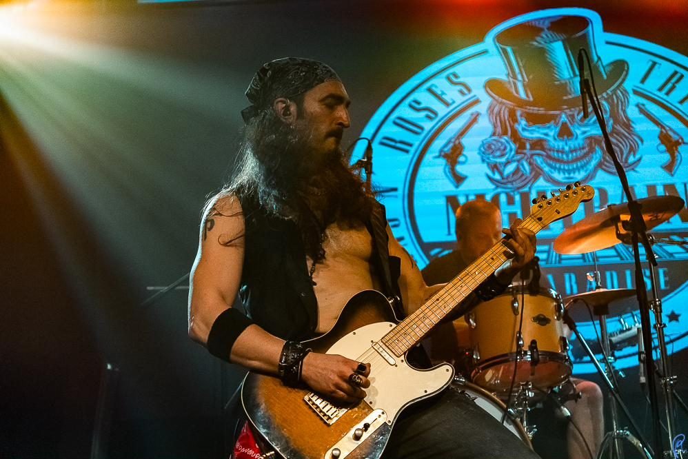 Guitarra rítmica en directo con el logo de la banda al fondo